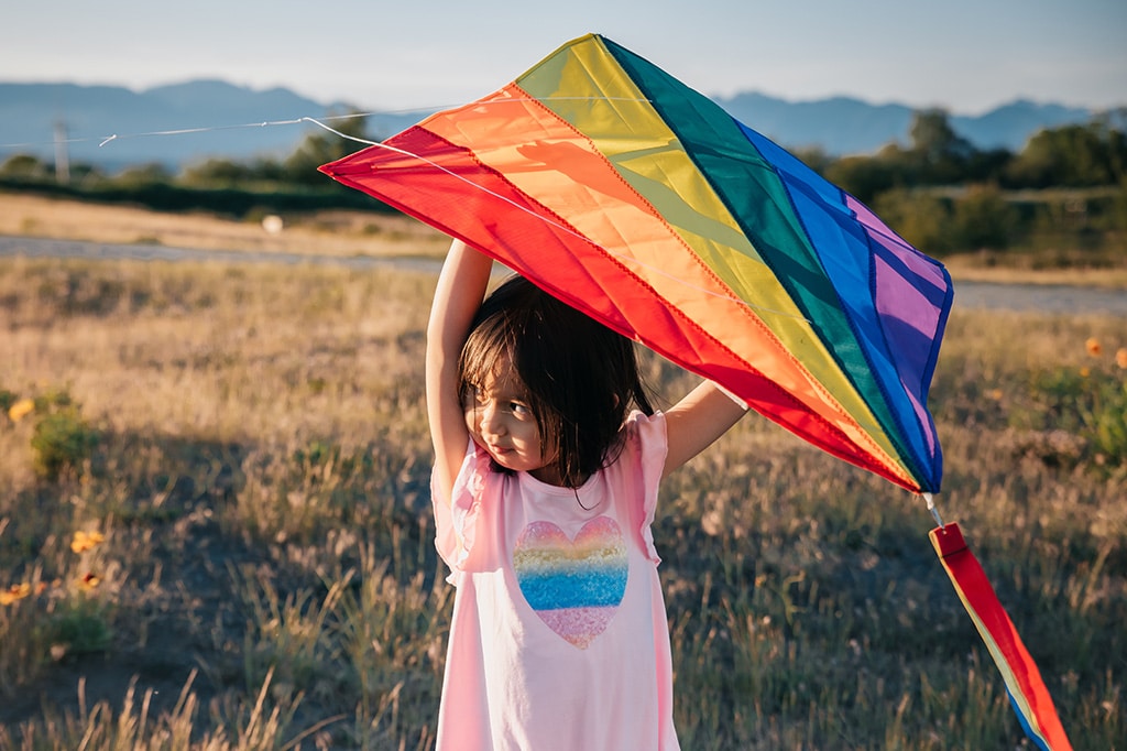 girl in pink shirt holds colorful kite
